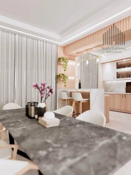 A render of a modern dining room with a marble-top table, flowing into a kitchen with a breakfast bar. The design emphasizes open, connected living.