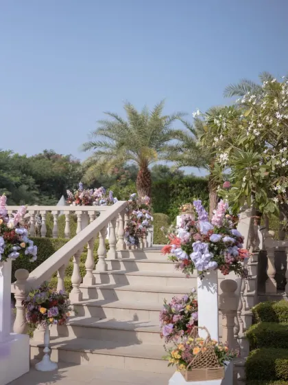 The stone staircase of the palace is decorated with beautiful floral arrangements in shades of lavender, pink, and orange.