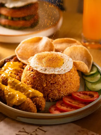 A close-up of seasoning being sprinkled over fried rice, capturing the individual grains of spice.
