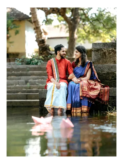 A serene and romantic portrait of a couple sitting by a temple pond, with paper boats floating in the water, adding a touch of whimsy.