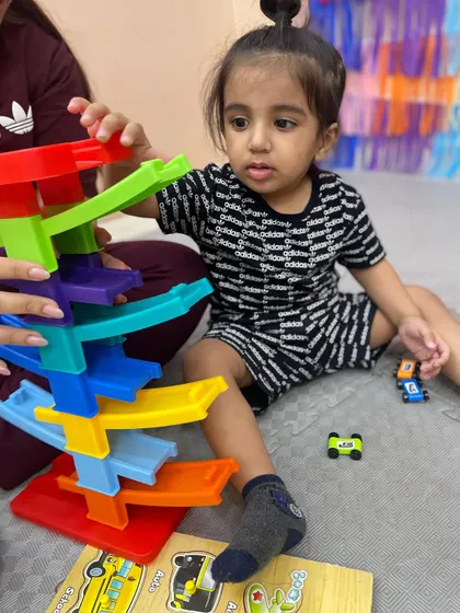 A child at our Pitampura center plays with a colorful car ramp, a toy that teaches cause and effect while developing fine motor skills and focus.