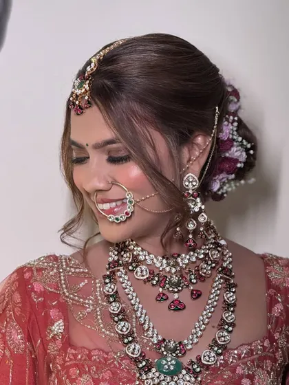 A happy bride smiling, adorned in a multi-layered kundan and polki set. The intricate details and colorful stones make this a truly special piece for a once-in-a-lifetime day.