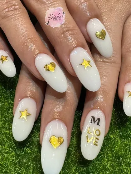 A lovely design with milky white nails, gold stars, and hearts, and the word "LOVE".