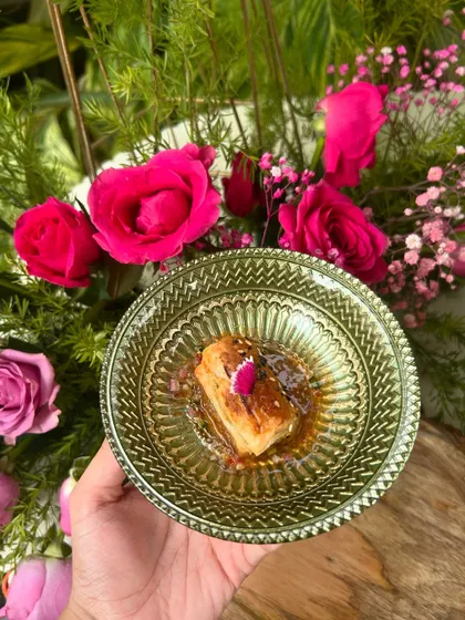 A cube of sesame-crusted paneer in a sweet and spicy sauce, beautifully plated in a green glass bowl.