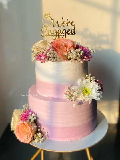 A beautiful two-tier engagement cake in shades of pink and lavender, adorned with fresh flowers. This one was a 2kg Pineapple cake, bringing a tropical flavor to the celebration.