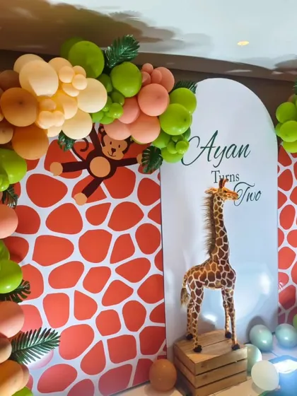 A closer view of the giraffe-print backdrop and balloon arch for Ayan's safari party. The mix of green and peach balloons adds a soft and modern touch to the theme.