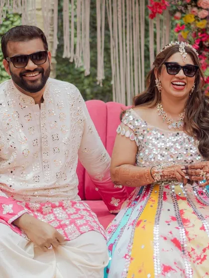 The happy couple, all smiles during their pastel-themed Haldi. The bride's multi-colored lehenga and the groom's ombre kurta perfectly complement the fun and modern decor.