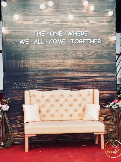 A fun and trendy photo booth with a rustic wooden backdrop and a "FRIENDS" themed sign.