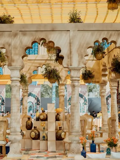 A closer look at the carved stone columns and arches of the central pavilion. The structure is adorned with hanging plants, adding a touch of greenery to the architectural element.