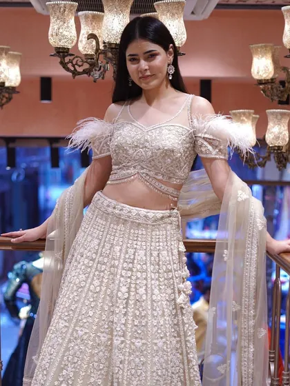 Drape yourself in opulence with this gold and white lehenga, complete with stunning feather sleeve detailing for a touch of modern glamour.
