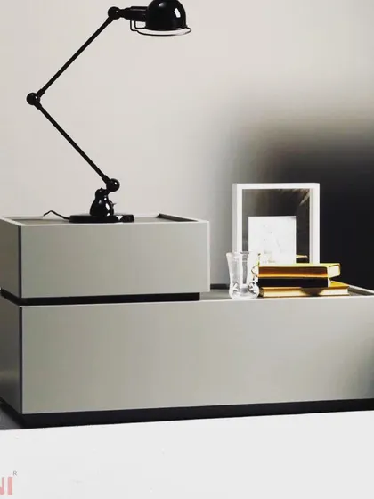 This modern bedside table features a minimalist, two-tiered design in a calm grey finish. Its clean lines and simple form provide a functional surface for a lamp and essentials without adding clutter to your sleeping space.