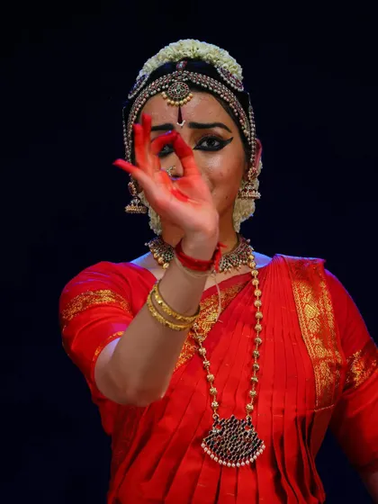 A powerful mudra held close to the face, indicating a specific thought or dialogue in the narrative of the dance.