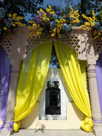 A decorated archway with bright yellow drapes and floral toppers, framing a window of the palace. This shows how we use decor to complement existing architecture.