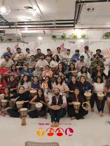 A group photo from a corporate session, filled with happy faces and djembes. This is the "after" picture, showing the tangible result of a session focused on connection and stress release.