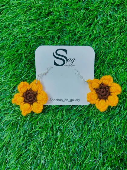 A pair of my cheerful sunflower crochet earrings. These handmade floral earrings are crafted with bright yellow and brown yarn, perfect for adding a touch of sunshine to your day.