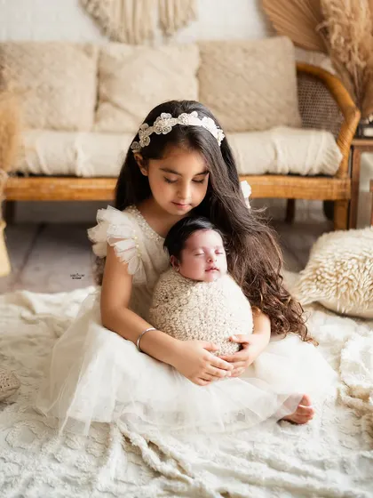 A big sister carefully holding her new baby sibling, a beautiful moment of new responsibility and love.