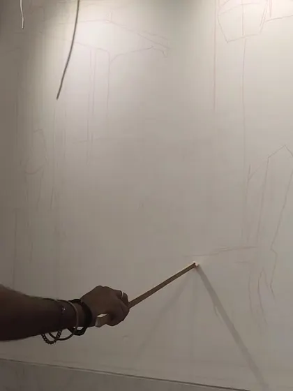A close-up showing my hand as I draw the initial fine lines for the composition directly onto the wall. Precision at this early stage ensures the final painting has a solid structural foundation.