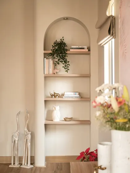 Even small spaces can make a powerful statement. This arched alcove features warm oak shelving for curated objects, turning a simple nook into a beautifully composed display of personal stories.