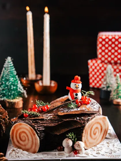 A classic Chocolate Yule Log (Bûche de Noël), decorated to look like a log from a winter forest. Complete with a tiny snowman and meringue mushrooms, it's a traditional centerpiece for your Christmas table.