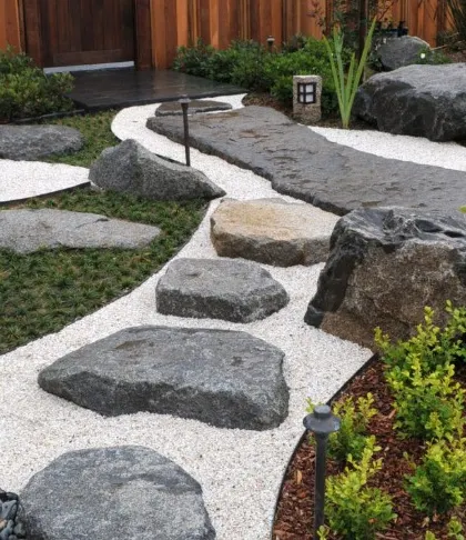 This is a classic Zen garden design featuring a pathway of large, irregular stepping stones set in white gravel. The careful placement of rocks and minimal planting creates a space that encourages contemplation.