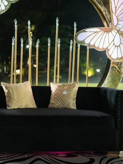 A close-up of the plush black sofa with gold sequined cushions, the centerpiece of the butterfly-themed photo booth.