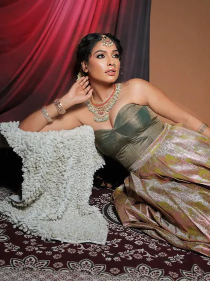 A relaxed, regal pose. The makeup enhances the model's features, with a focus on glowing skin and defined eyes that work beautifully with the unique outfit.