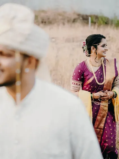 A creative shot with the bride in focus, smiling, while the groom is a soft presence in the foreground.