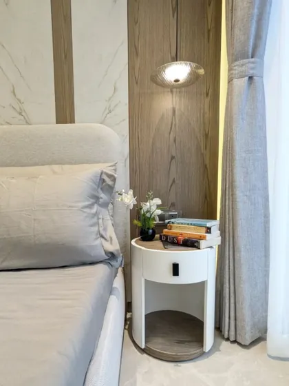 A close-up of a modern circular bedside table, a smart choice for smaller bedrooms. Its unique design provides storage without taking up too much visual or physical space.