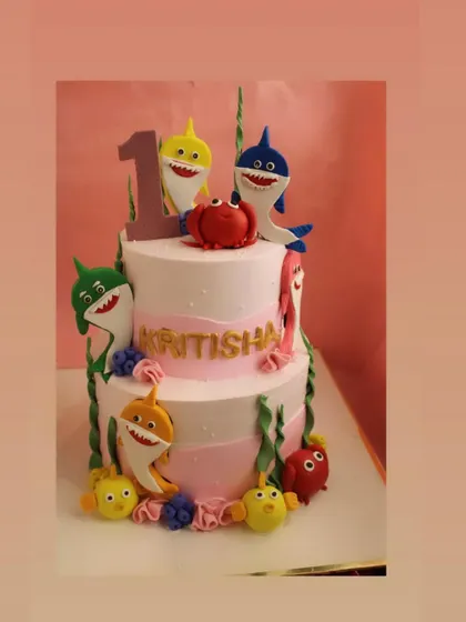 A two-tier Baby Shark cake for a first birthday. This 3kg cake is adorned with the entire shark family, made from detailed fondant work.