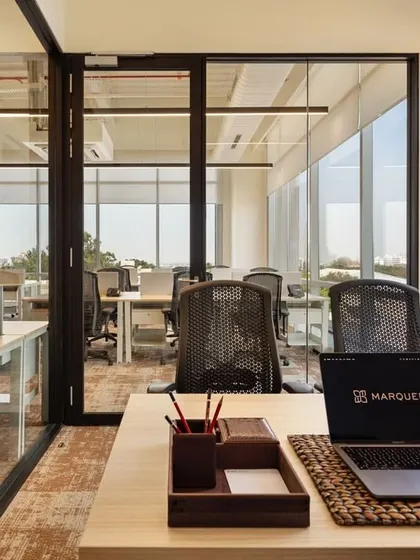 A view from a desk at CorporatEdge, Bangalore, looking out into the open office. The use of glass walls for cabins maintains a sense of transparency and connection across the entire floor.