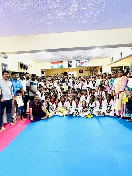Students, coaches, and proud parents gather for a photo after a successful belt promotion ceremony.