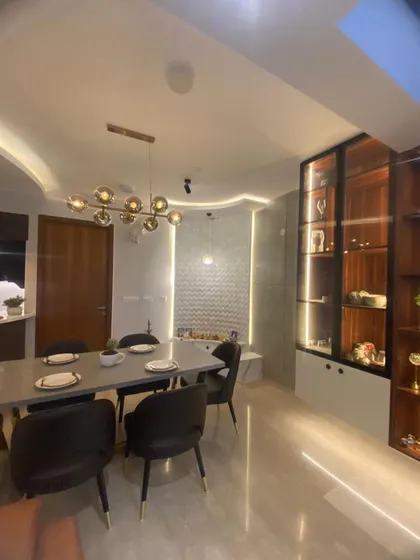 The elegant dining space, with a sleek table and comfortable chairs, is perfect for hosting dinner parties. The illuminated crockery cabinet provides both storage and a beautiful display.