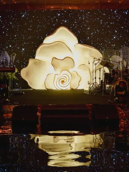 A giant, illuminated rose serves as a dramatic backdrop for the reception stage. This custom-built structure is a perfect example of how we create unique, artful focal points.