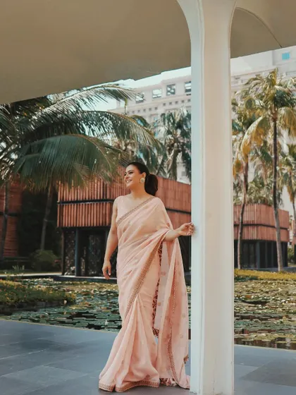 A candid moment that captures the grace and movement of the saree. The soft pink color is flattering and perfect for any celebratory occasion.