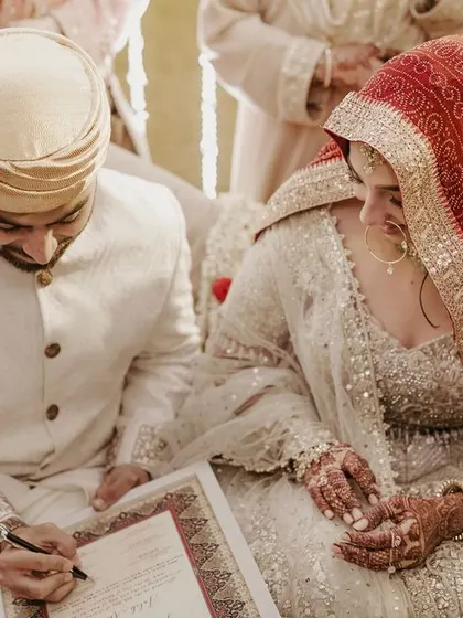 The groom signs the marriage contract during the Nikah ceremony, with his bride by his side.