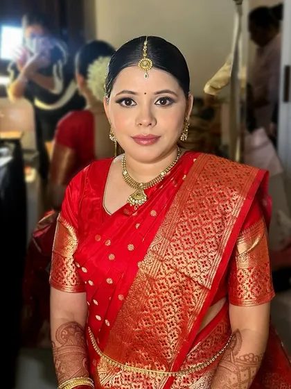 A portrait of a Maharashtrian bride. The lighting in the room highlights the clean, precise makeup application and the traditional gold jewelry.