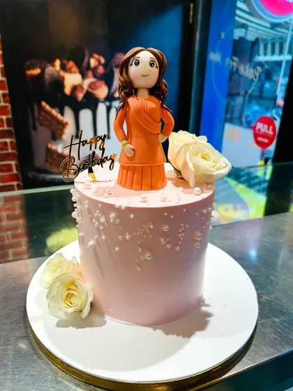 The full cake featuring the custom figurine, decorated with fresh white roses and edible pearls.