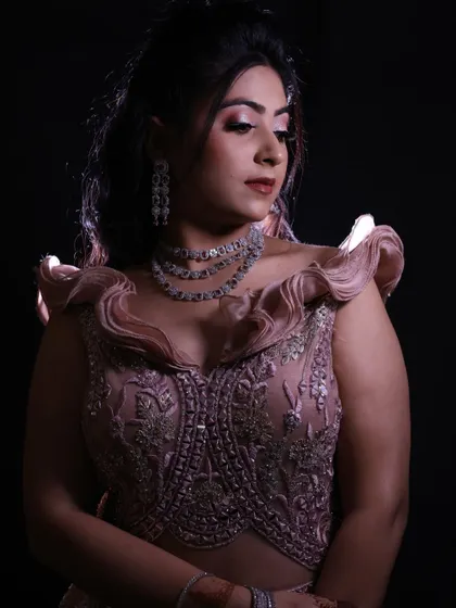 A close-up portrait of the model in the dusty pink engagement gown, showcasing the ruffled shoulders and detailed bodice against a black background.