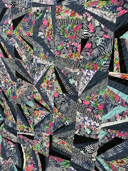 A close-up of the abstract strip-pieced quilt, showing the dynamic angles and mix of prints.