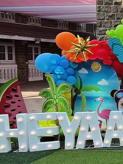 A lit-up name sign as part of the colorful and fruity pool party backdrop.