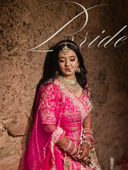 A stunning bridal portrait against a rustic stone wall. The dramatic lighting and her elegant pose create a powerful and artistic image that highlights her beauty and grace.