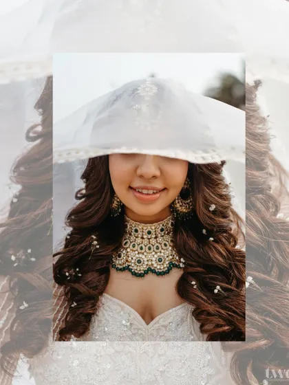 A creative close-up of the bride, with her face partially covered by her delicate veil. It's a playful yet elegant shot that highlights her beautiful smile and jewelry.