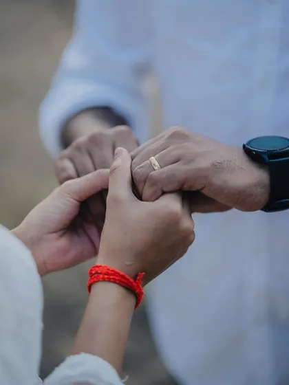 A close-up shot of a couple holding hands, focusing on their intertwined fingers and the engagement ring. A simple, powerful symbol of their bond.