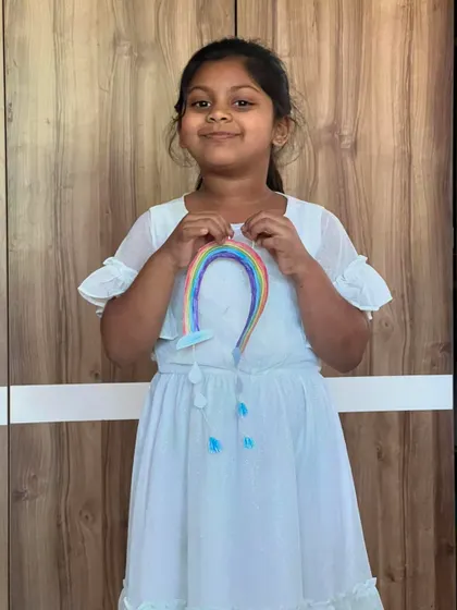 A sweet smile from a little artist holding her beautiful hanging rainbow craft.