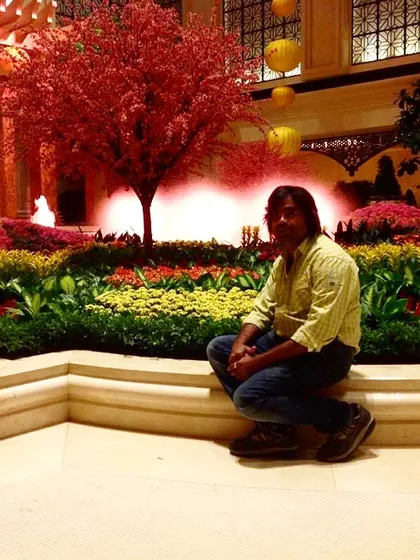 A stunning indoor conservatory garden, likely from a hotel in Las Vegas. The vibrant red trees and manicured flower beds create a surreal and beautiful environment.