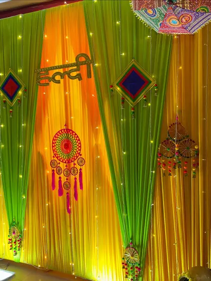 The vibrant colors of the Haldi backdrop, featuring yellow and green drapes, are perfect for photos. The traditional hangings and 'Haldi' sign complete the festive look.