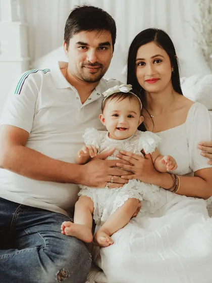A classic, happy family portrait. The parents and their baby are all smiles for the camera, creating a timeless keepsake.