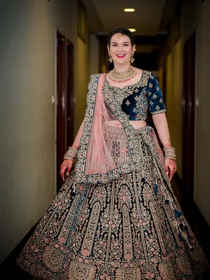 A full-length portrait of the bride in her stunning blue and pink lehenga, showcasing the intricate embroidery.