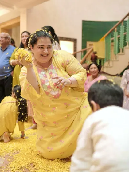 A moment of pure joy during a celebration. The client is comfortable and happy in her custom yellow mul mul chanderi suit, perfect for festive gatherings.