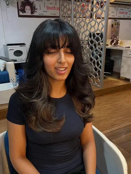 The full bangs and feathered layers are a classic combination.